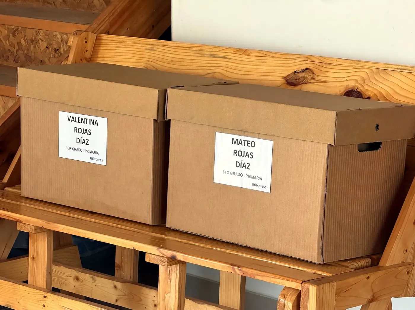 Dos cajas de pedido UtilXpress rotuladas con el nombre y grado de cada alumno, listas para entregar
